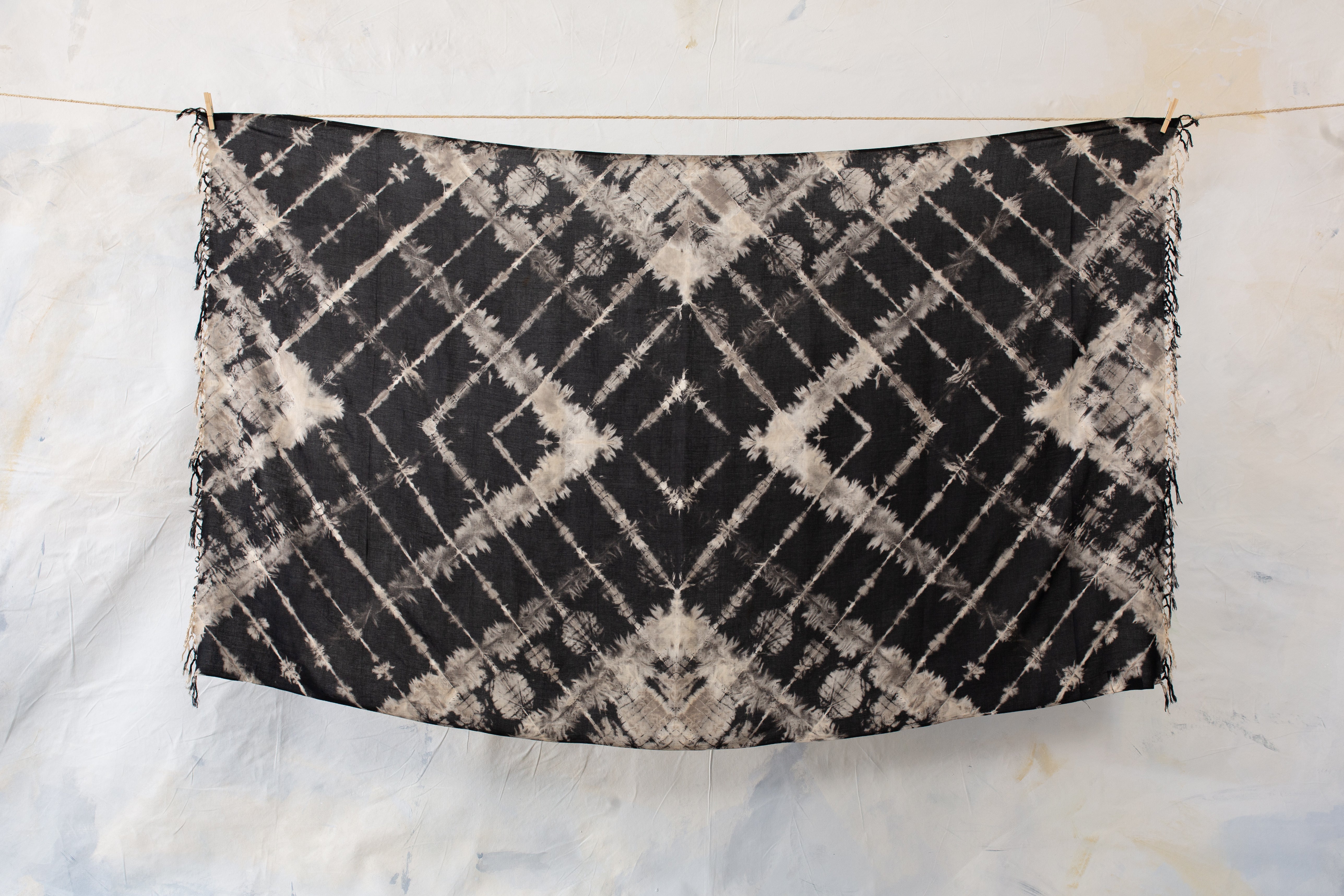Großer weicher Viskose-Sarong in Schwarz mit orangefarbenem Batik-Zick-Zack-Muster und beige-grauen Einschlüssen, mit Fransen, aufgespannt
