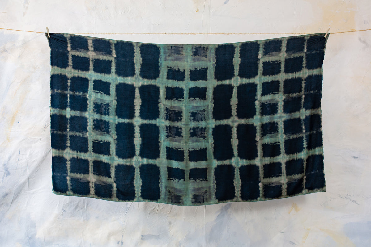 Aufgespannter dunkelblauer Sarong mit geometrischem Batikmuster in Türkis und Beige