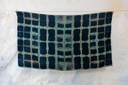 Aufgespannter dunkelblauer Sarong mit geometrischem Batikmuster in Türkis und Beige