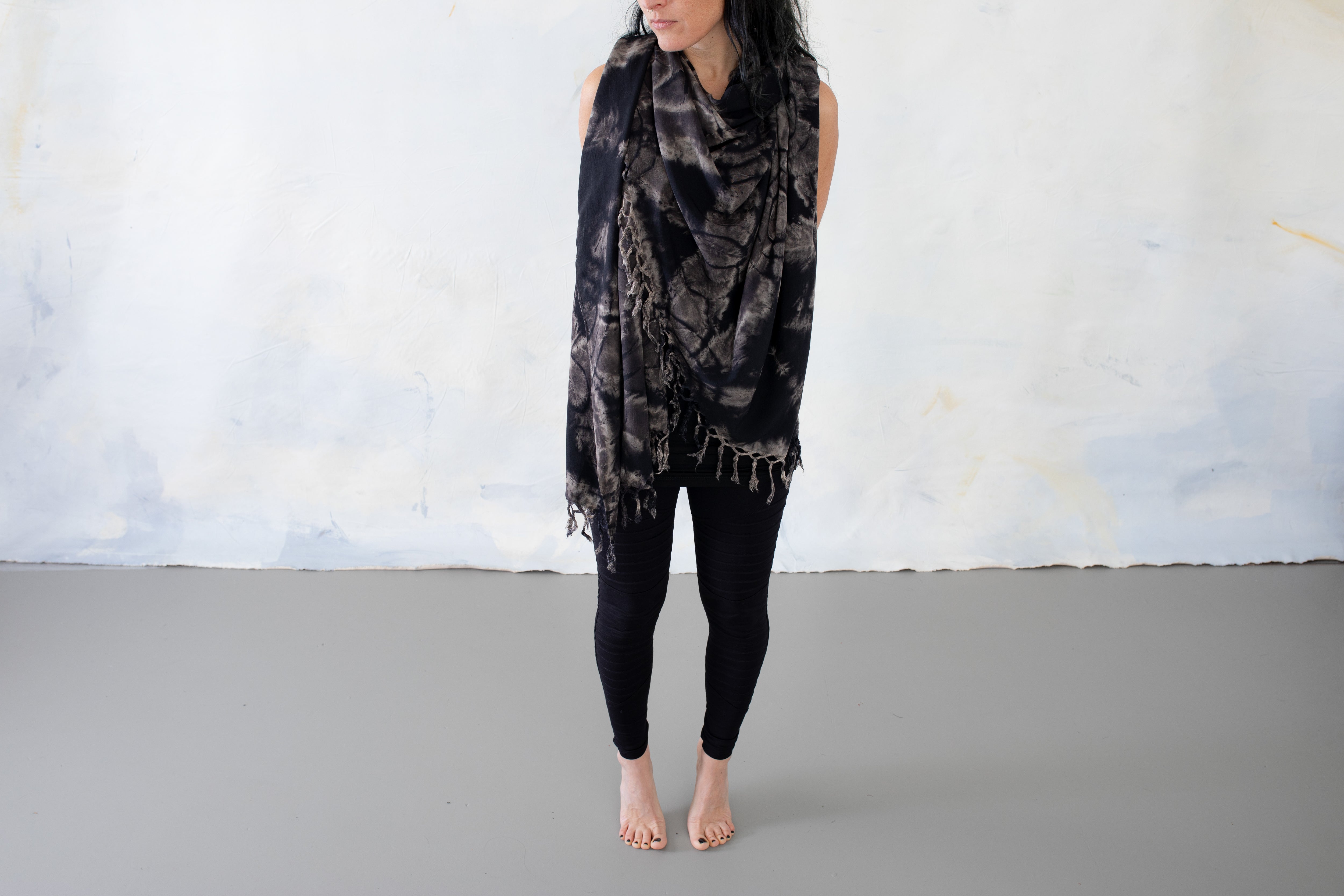 Model trägt einen schwarzen Sarong mit grau-beigem floralem Batikmuster und Fransen um Hals und Oberkörper
