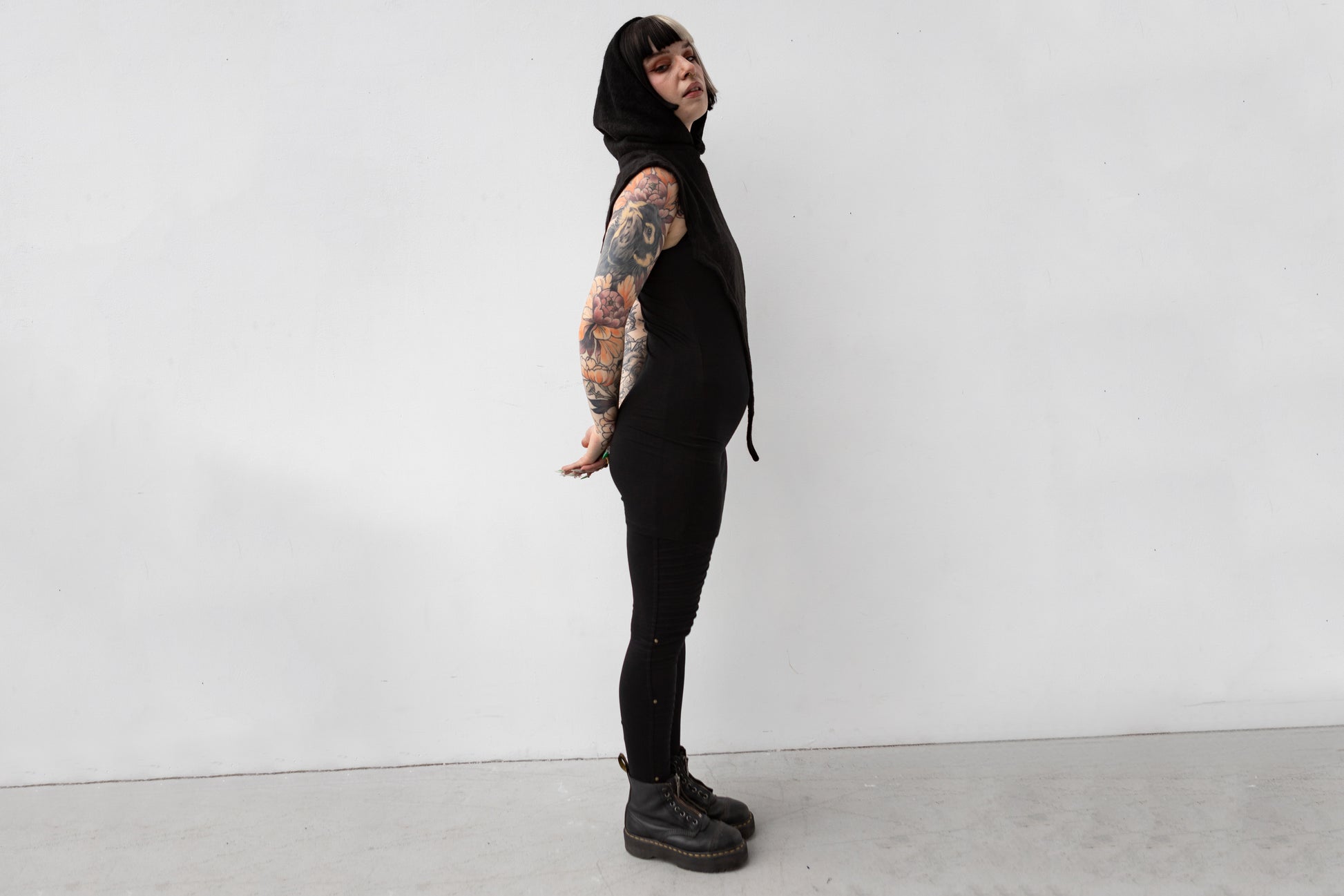 Weiblich gelesenes Model trägt Schalkapuze mit asymmetrischem Schnitt und großem Zipfel