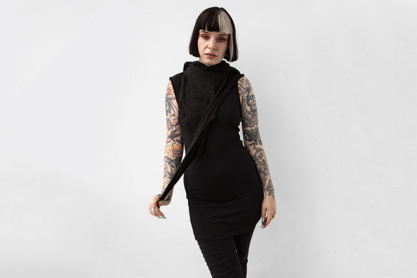 Weiblich gelesenes Model trägt ausgefallene schwarze Strick-Schalkapuze im Darf Fahion Look