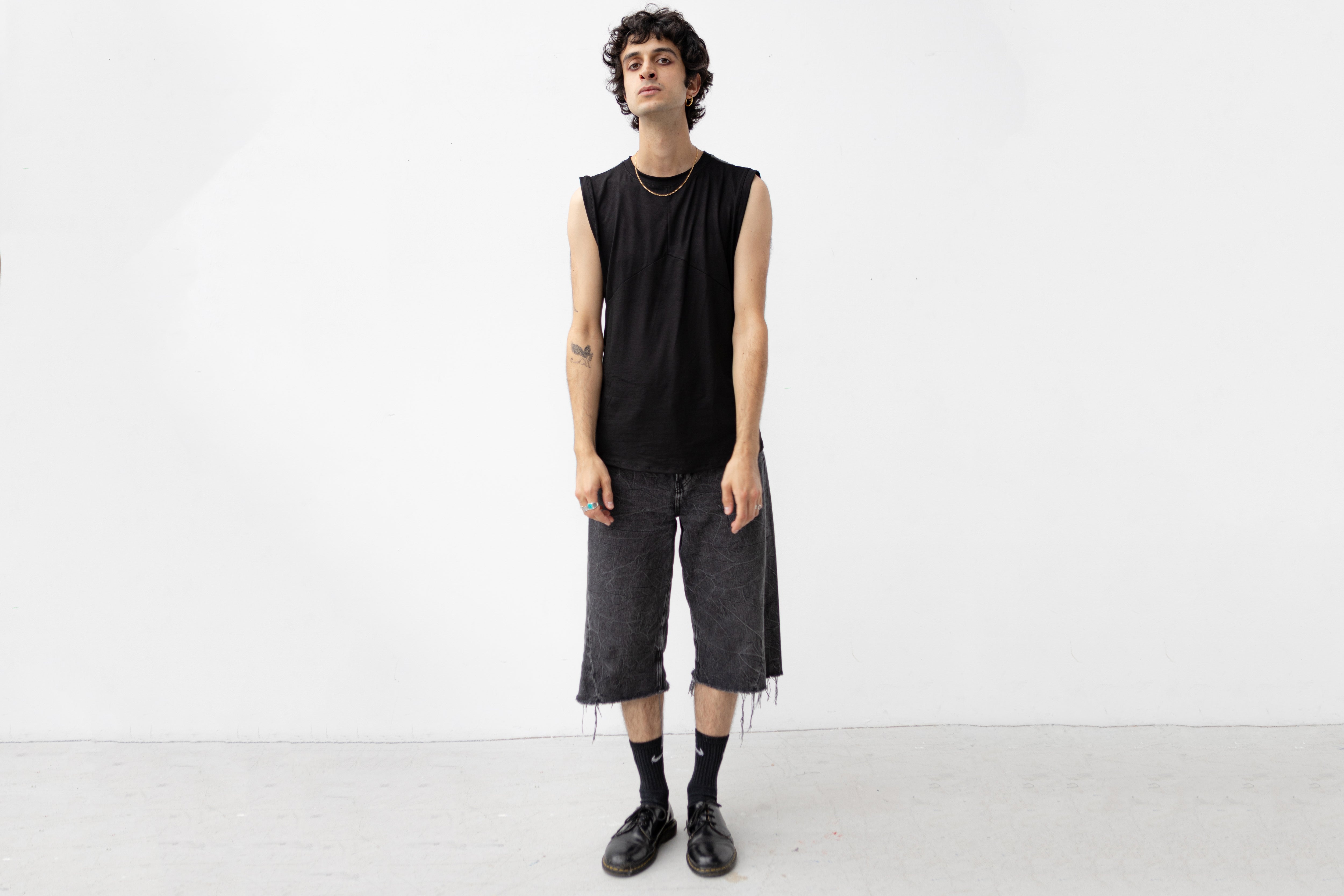 Minimalistisches schwarzes Tanktop mit Rückendetail getragen von männlich gelesenem Model.