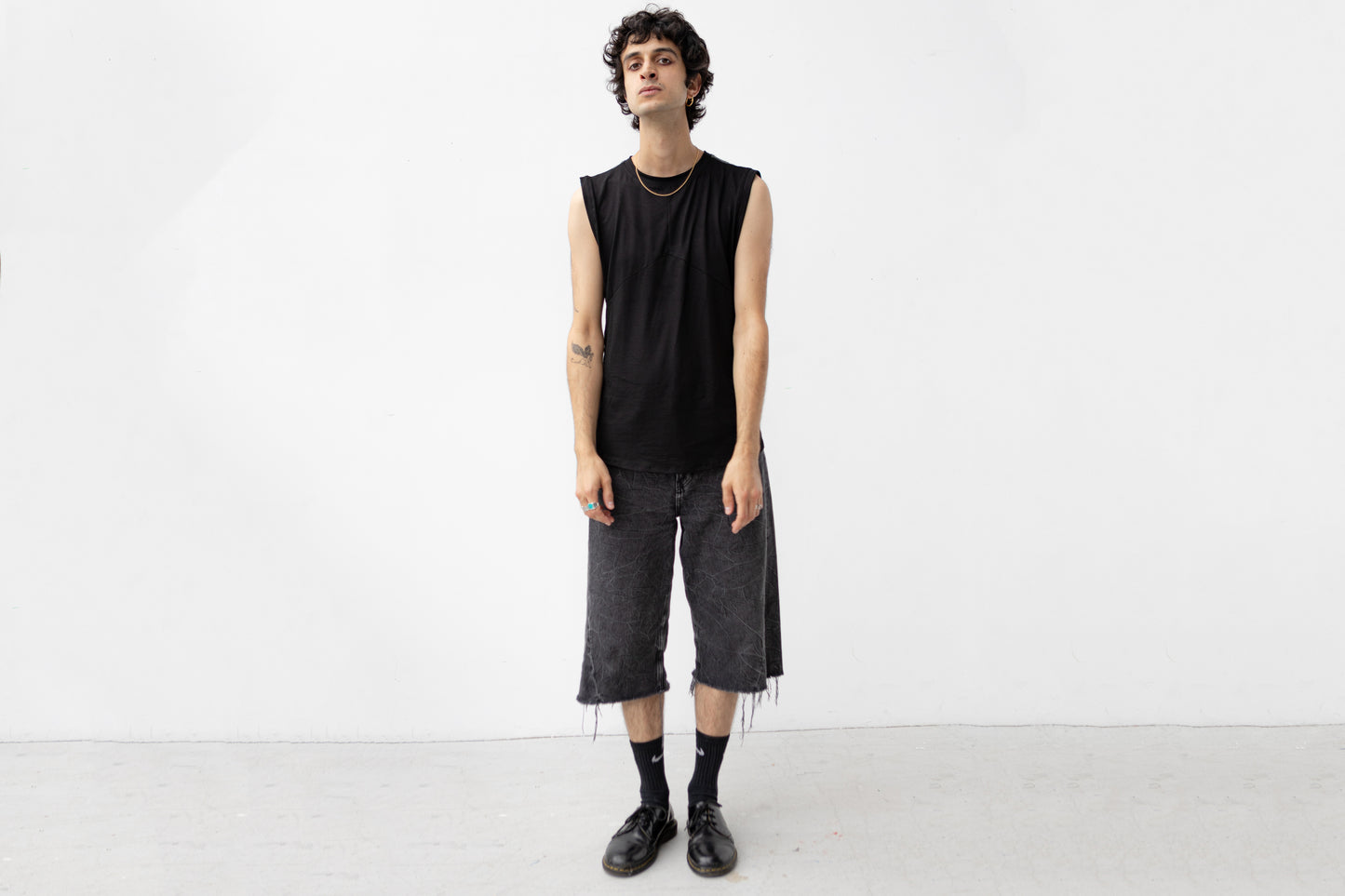 Minimalistisches schwarzes Tanktop mit Rückendetail getragen von männlich gelesenem Model.