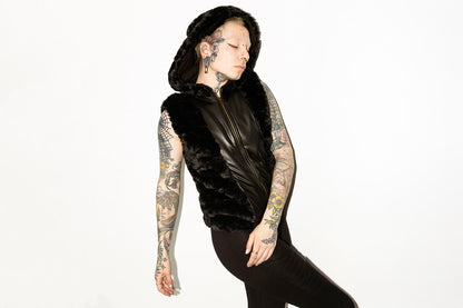 Ausdrucksstarkes Model mit schwarzer Kunstfellweste mit Kunstleder-Applikationen und Leggings mit Nahtstruktur